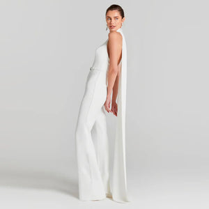 Woman wearing a white sleeveless jumpsuit with a slit on a plain background