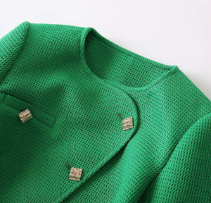 Green knitted cardigan with button details on a light gray background