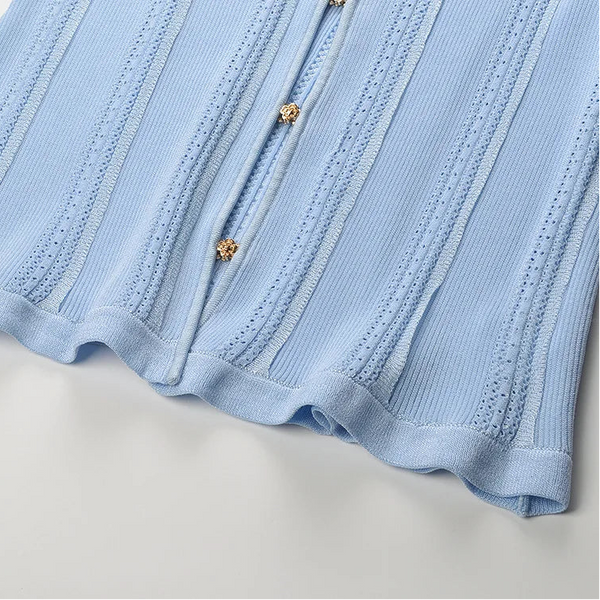 Close-up of a light blue ribbed fabric with buttons on a white background