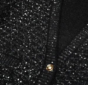 Close-up of a black sequined fabric with gold buttons.