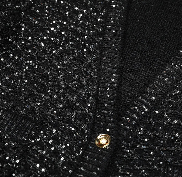 Close-up of a black sequined fabric with gold buttons.