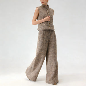 Person wearing a brown sleeveless top and wide-leg pants on a white background