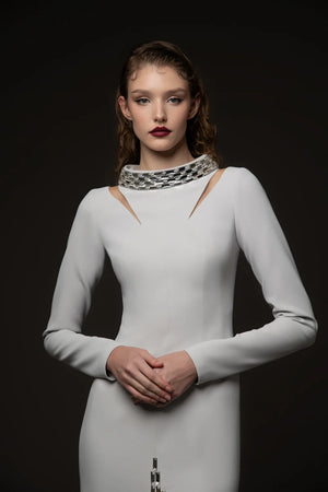 Woman wearing a white dress with cut-out shoulders against a black background