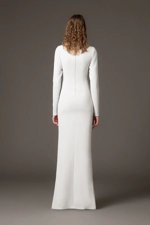 Woman wearing a long white dress against a gray background