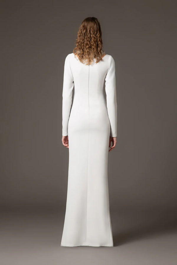 Woman wearing a long white dress against a gray background