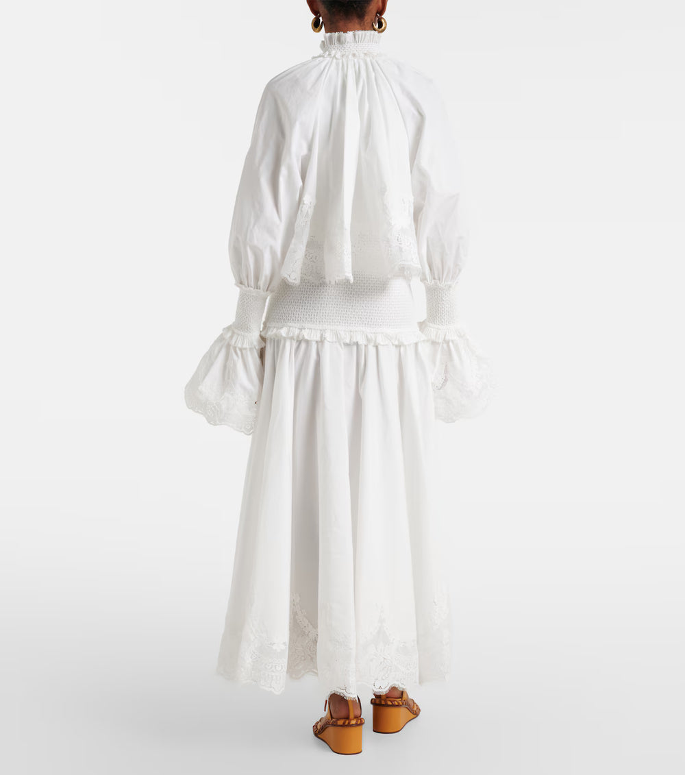 Person wearing a white dress with long sleeves and a skirt, standing against a white background.