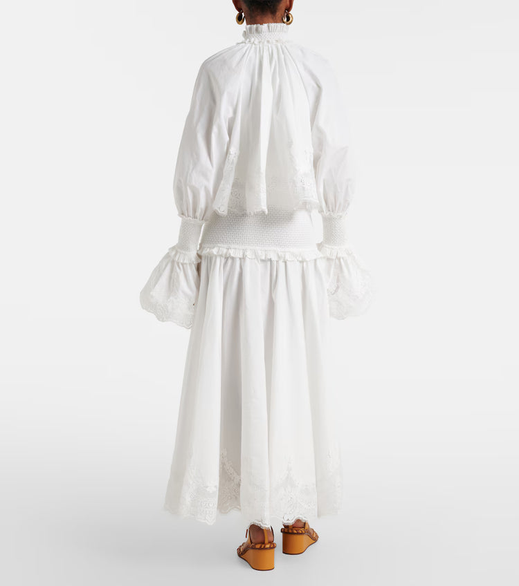 Person wearing a white dress with long sleeves and a skirt, standing against a white background.