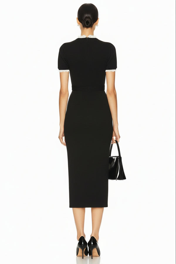 A model wearing a black short-sleeve midi dress with white buttons and a decorative belt buckle, holding a black handbag against a plain white background.