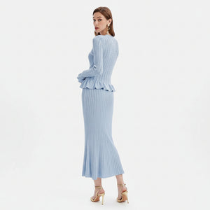 Woman wearing a light blue ribbed dress with a peplum waist on a white background