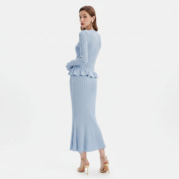 Woman wearing a light blue ribbed dress with a peplum waist on a white background