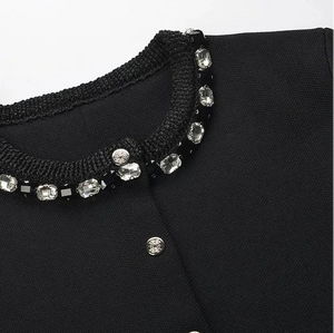 Black collar with crystal embellishments on a black garment against a white background