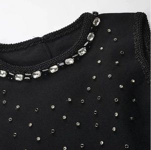 Black garment with beaded embellishments on a white background