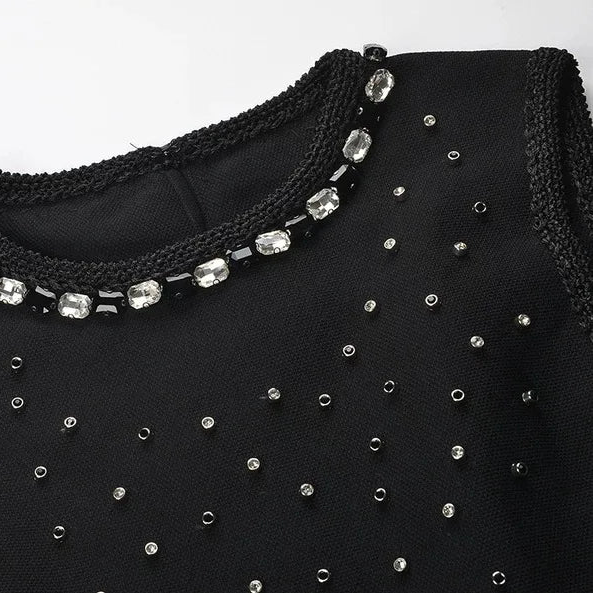 Black garment with beaded embellishments on a white background