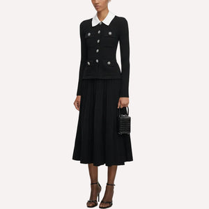 Woman wearing a black outfit with a white collar, holding a black handbag on a white background