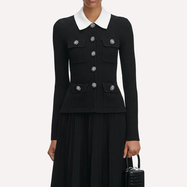 Black ribbed sweater with white collar and decorative buttons on a plain background