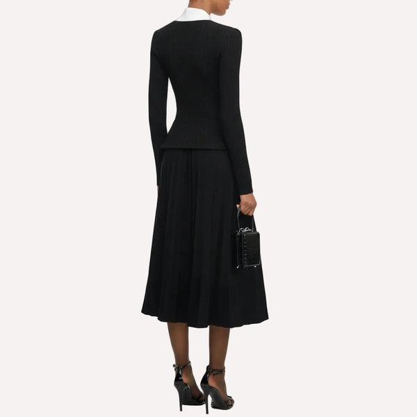 Person wearing a black dress with a white collar on a white background