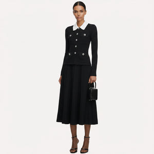 Woman wearing a black outfit with a white collar, holding a black handbag on a white background