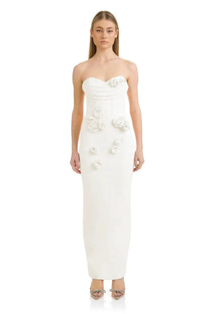 Woman wearing a strapless white gown with floral embellishments on a white background
